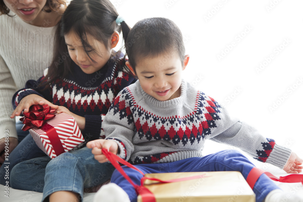 お母さんと、大きなプレゼントを開ける男の子と女の子。