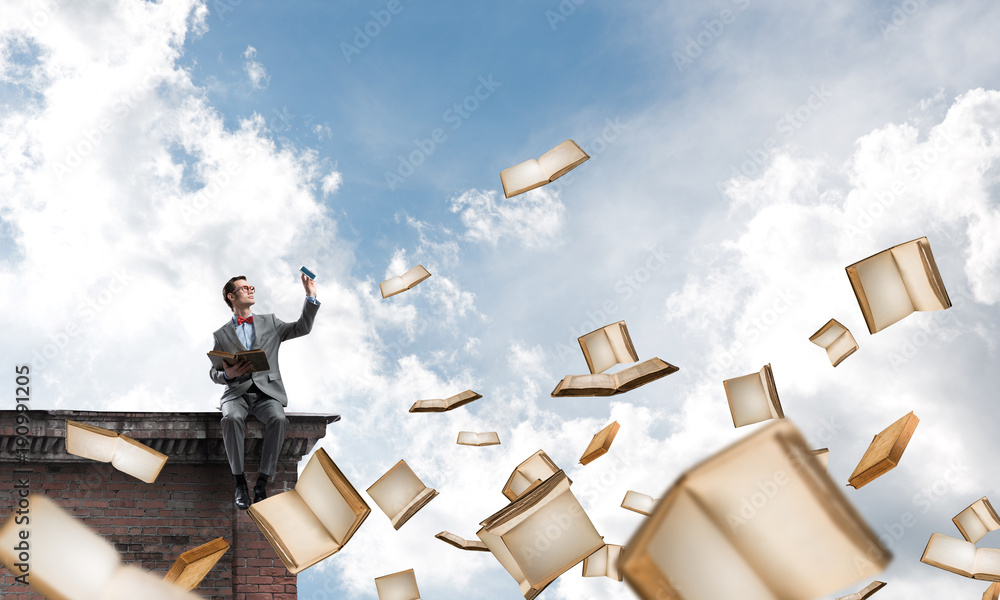 Young businessman or student studying the science and books flying around