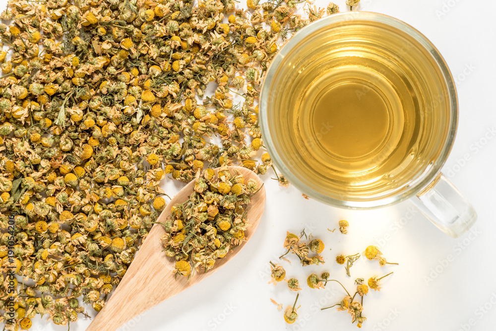 Dry Camomile Tea in a spoon on white background.