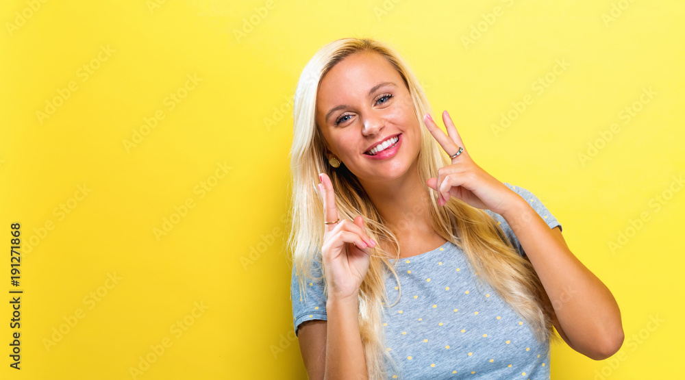 Young woman giving the peace sign on a solid background