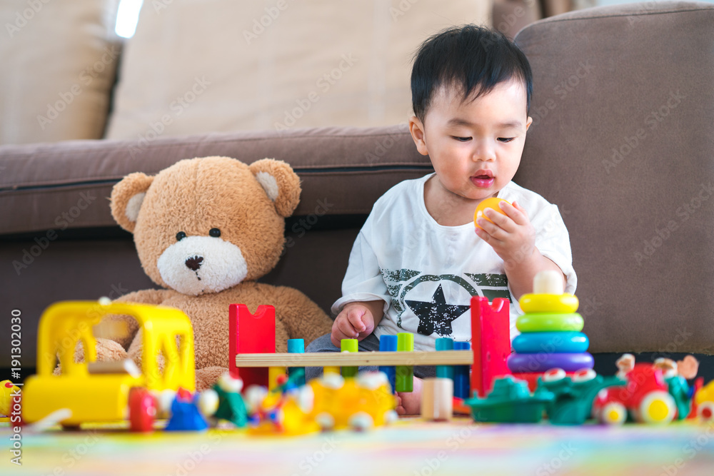 Asian boy play a toy with teddy bear in lieving room