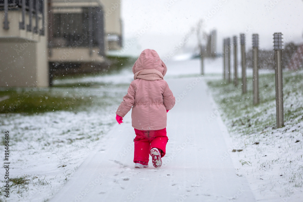 穿着冬季夹克在雪地上奔跑的可爱女孩