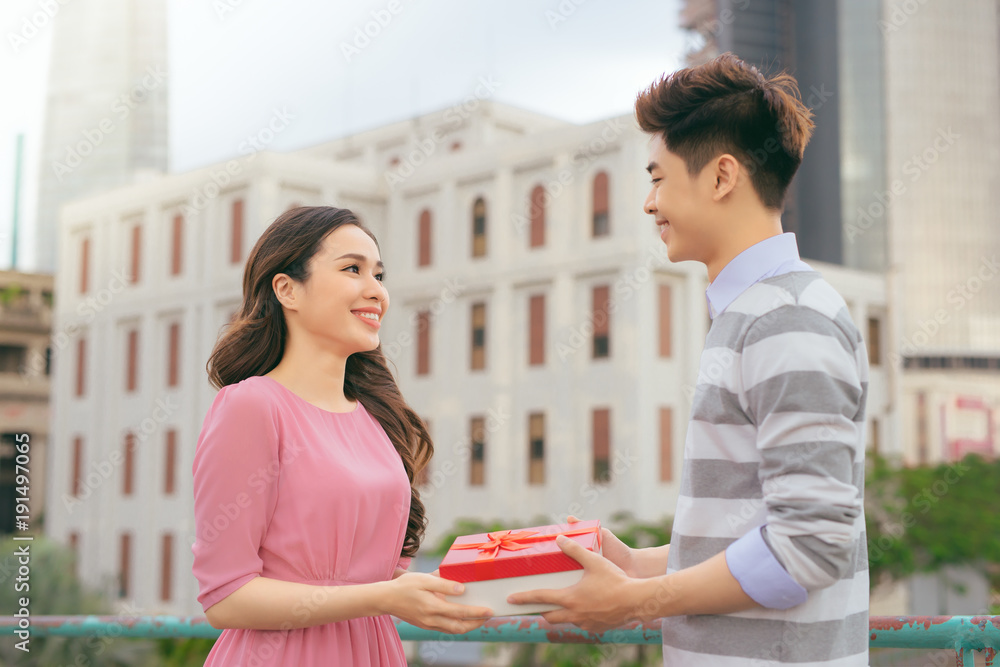 男人给女人送礼物。亚洲情侣在户外热恋