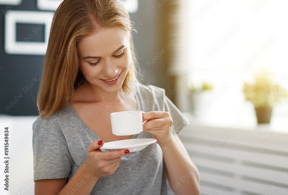 happy young woman with cup of morning coffee in bed