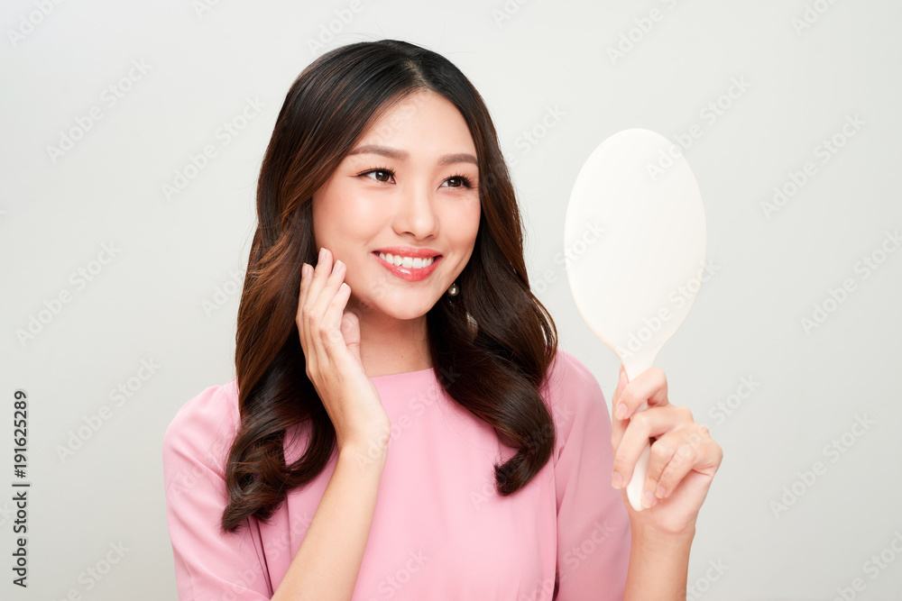 Asian woman looking at the mirror and touching on her skin.