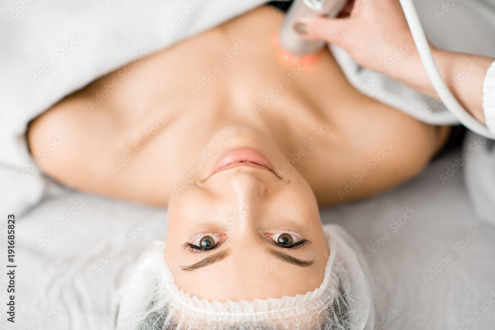 Young woman during a massage on the neckline with professional tool at the medical center