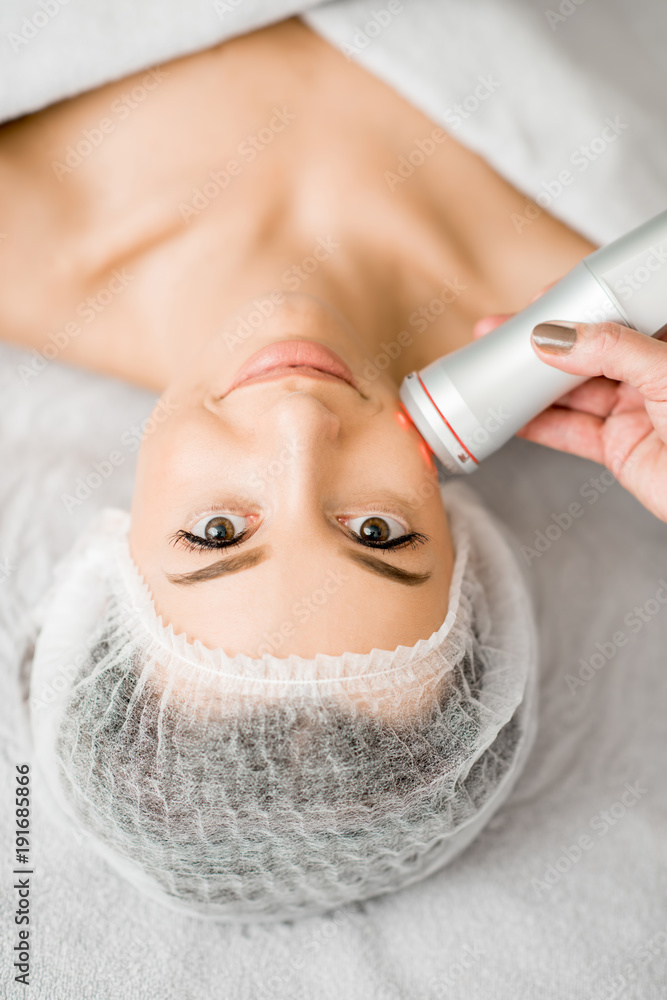 Young woman during a facial massage with professional tool at the medical center