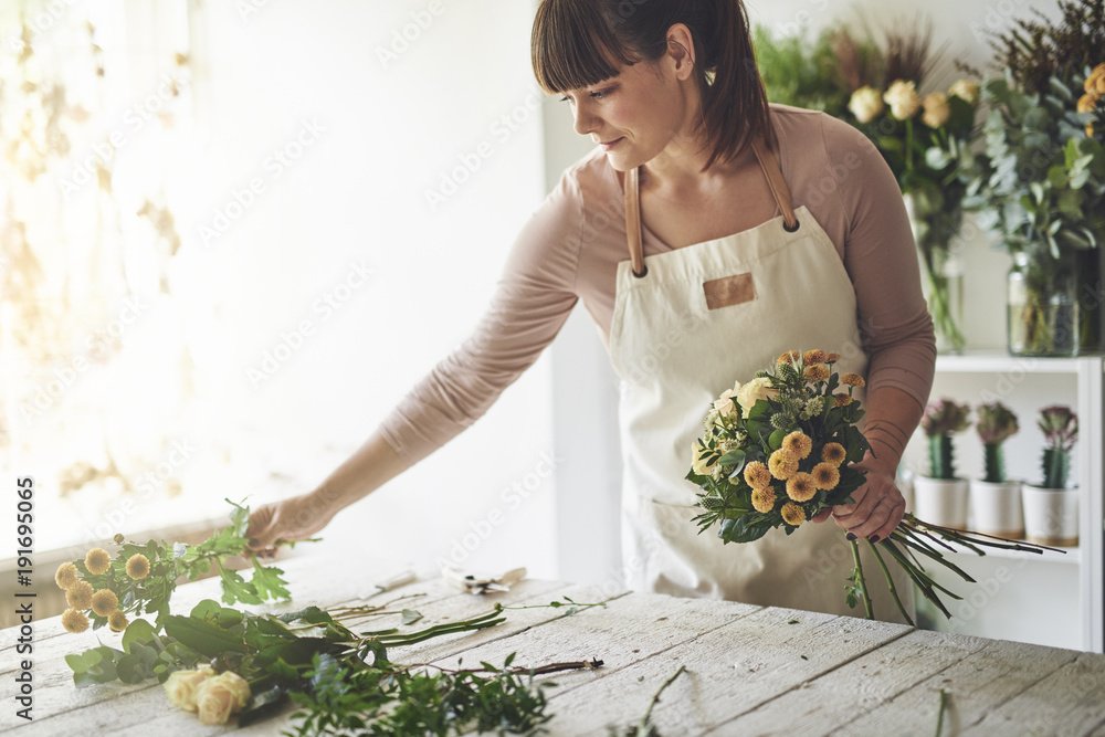 Young woman making a floral arrangement in her flower shop