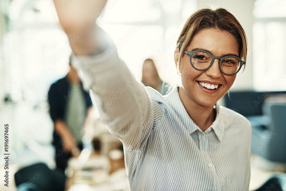 Smiling young businesswoman standing in an office high fiving