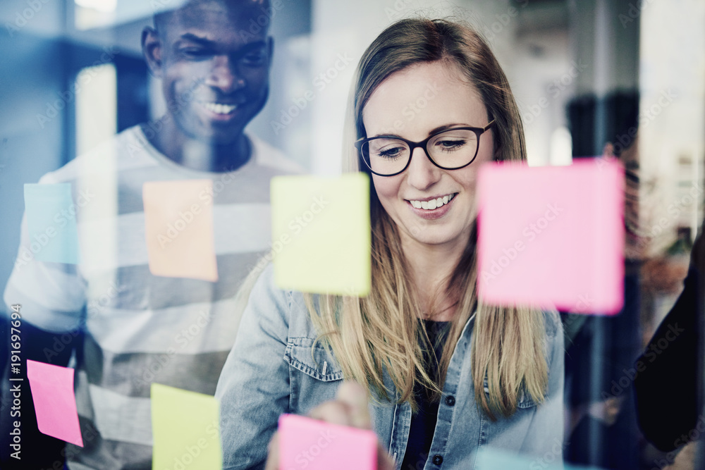 Diverse businesspeople brainstorming with sticky notes on a glass wall