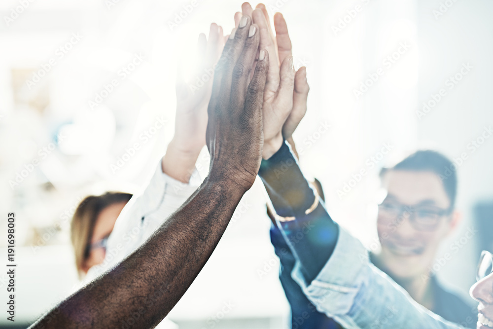 Group of diverse businesspeople high fiving together in an office