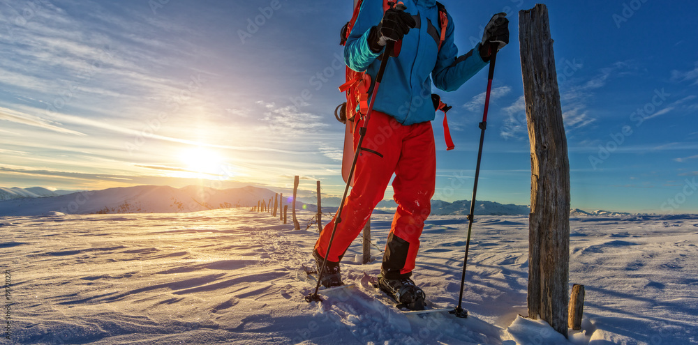 Snowboarder walking on snowshoes in powder snow.