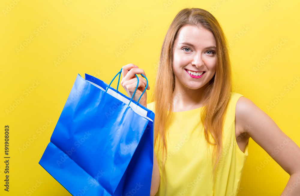 Young woman holding a shopping bag on a yellow background