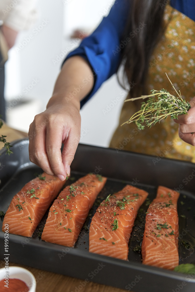 在生三文鱼中添加香料和草药的女人