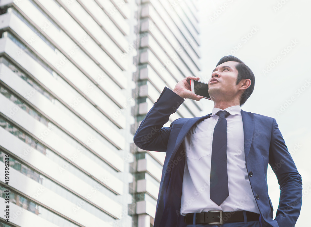 business, technology and people concept - serious businessman with smartphone talking over office bu