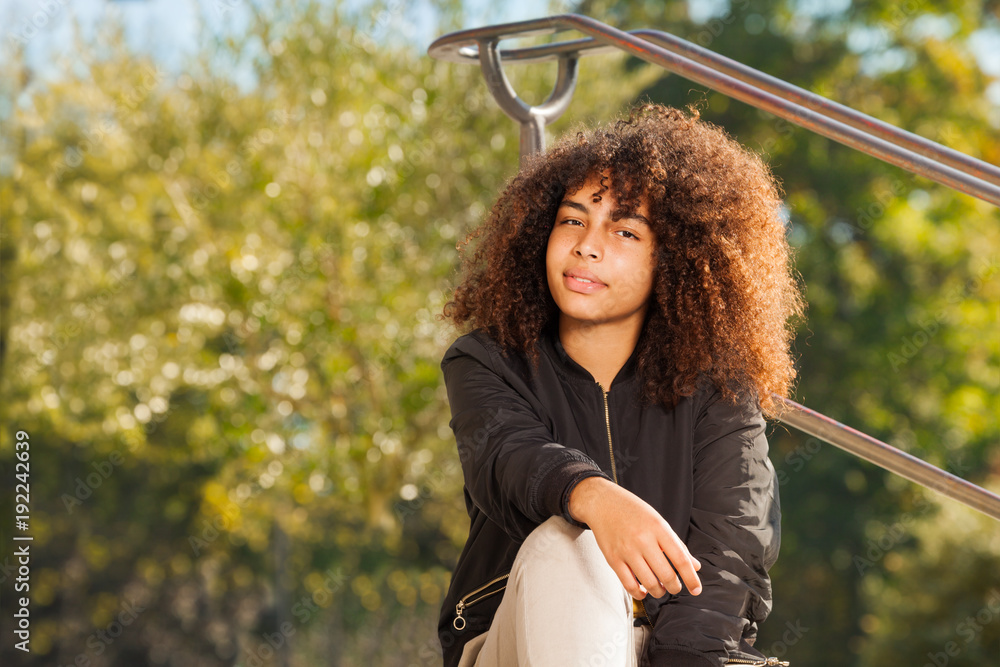 African teenage girl sitting at the park in autumn