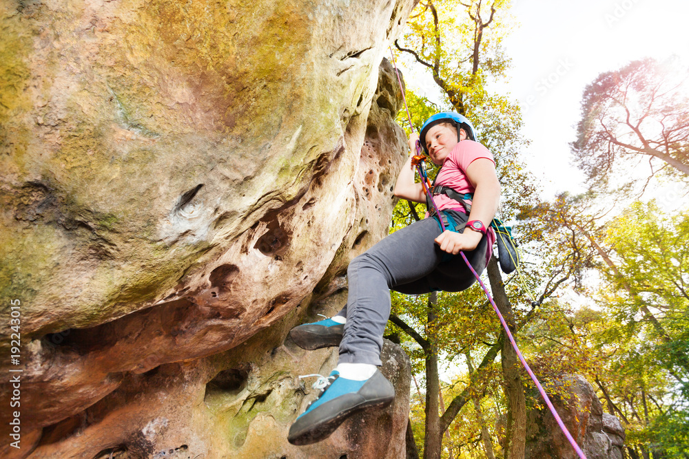 Teenage rock climber exercising at sunny day