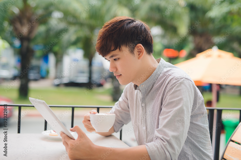 Young male freelancer using digital tablet in comfortable coffee shop