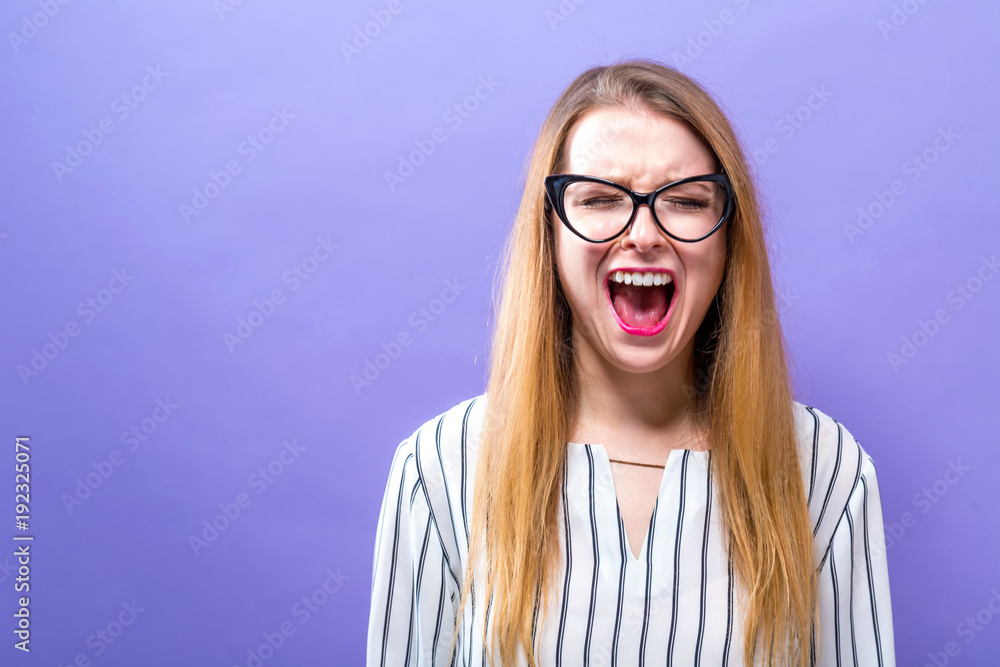 Young woman screaming on a solid background