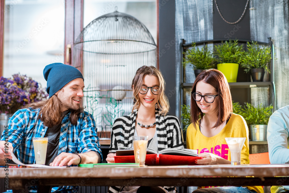 Group of friends dressed casually working or studying together at the big table in the modern cafe i