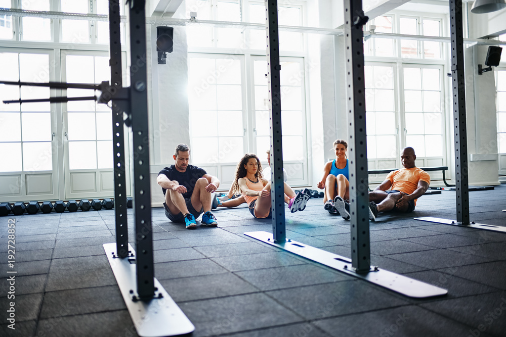 Focused group of people doing crunches together in a gym