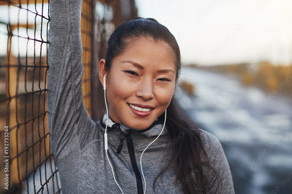 微笑的穿着运动服的亚洲女人慢跑前听音乐