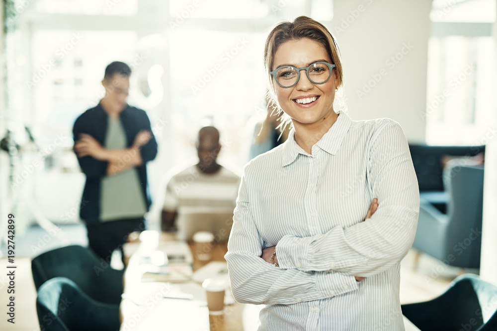 Young businesswoman in an office with coworkers in the background