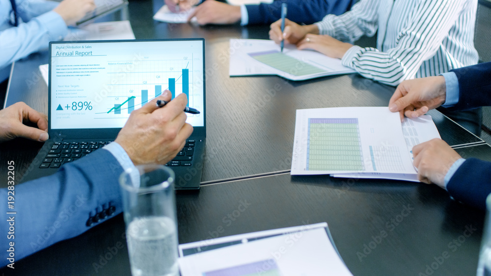 Shot of the Business Meeting Room Table with People Sharing Documents with Pie Charts and Statistics