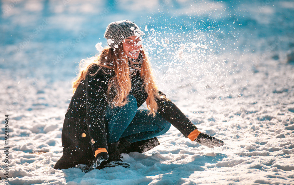 阳光明媚的冬日，微笑的女人向空中扔雪