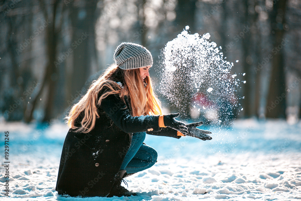 阳光明媚的冬日，微笑的女人向空中扔雪