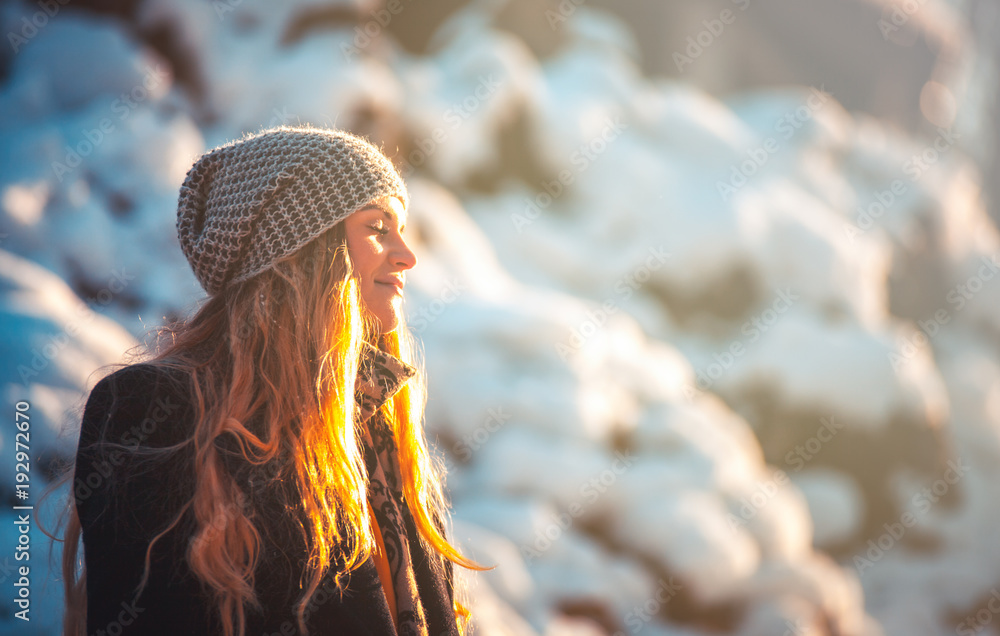 Smiling young woman during walk in the winter park at sunny day