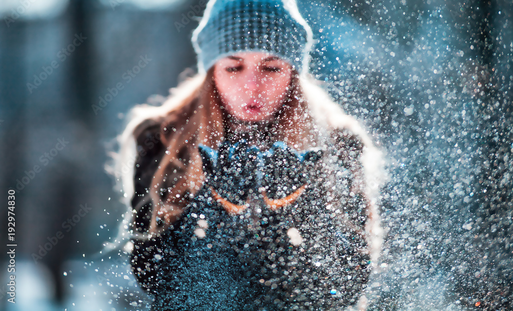 Winter woman blowing snow outdoor, flying snowflakes