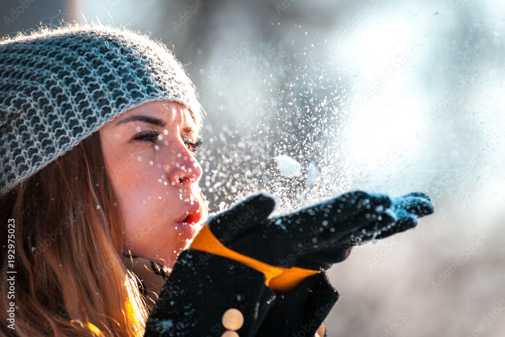 冬日女子晴天在户外吹雪，雪花纷飞