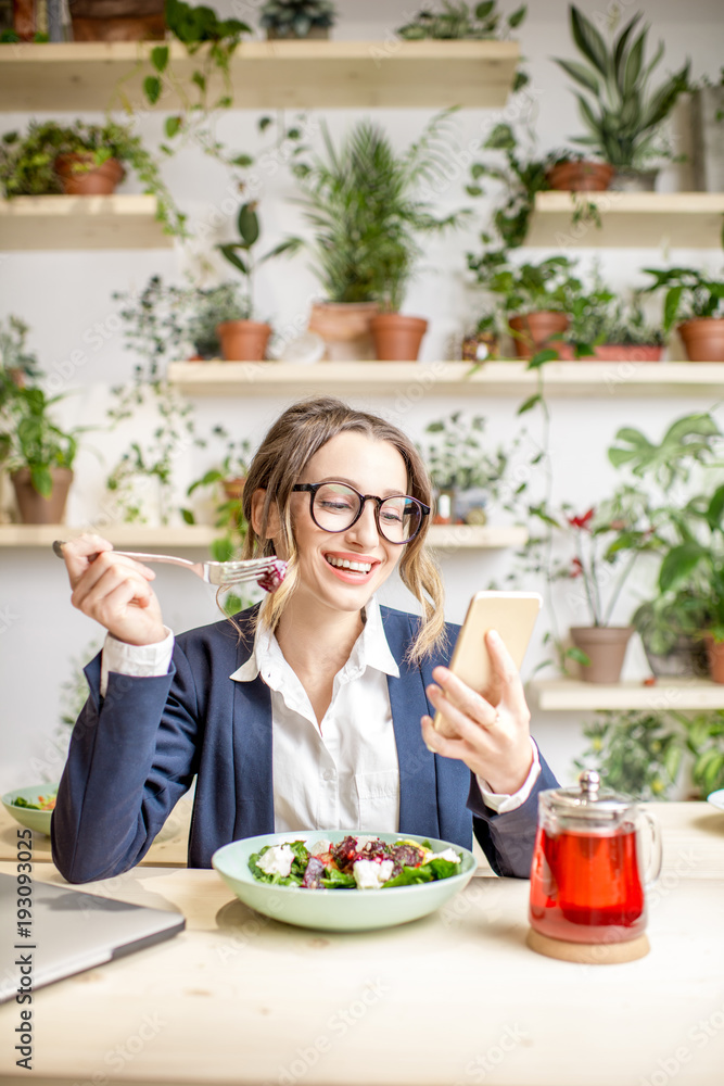 一位女商人在午餐时吃沙拉，坐在美丽的g上的素食餐厅