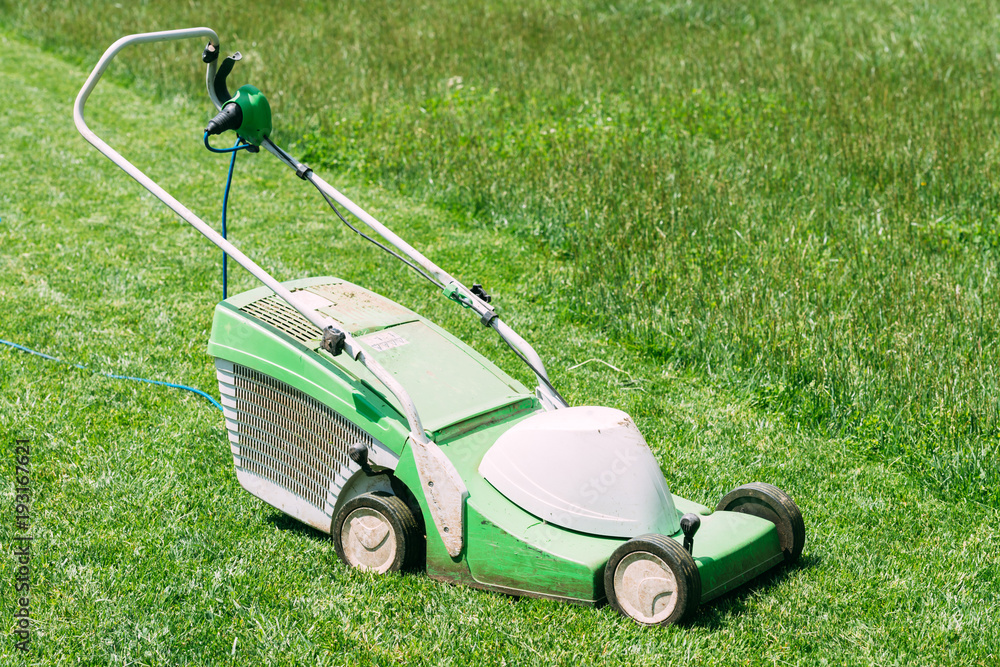 Electric lawn mower on green grass closeup