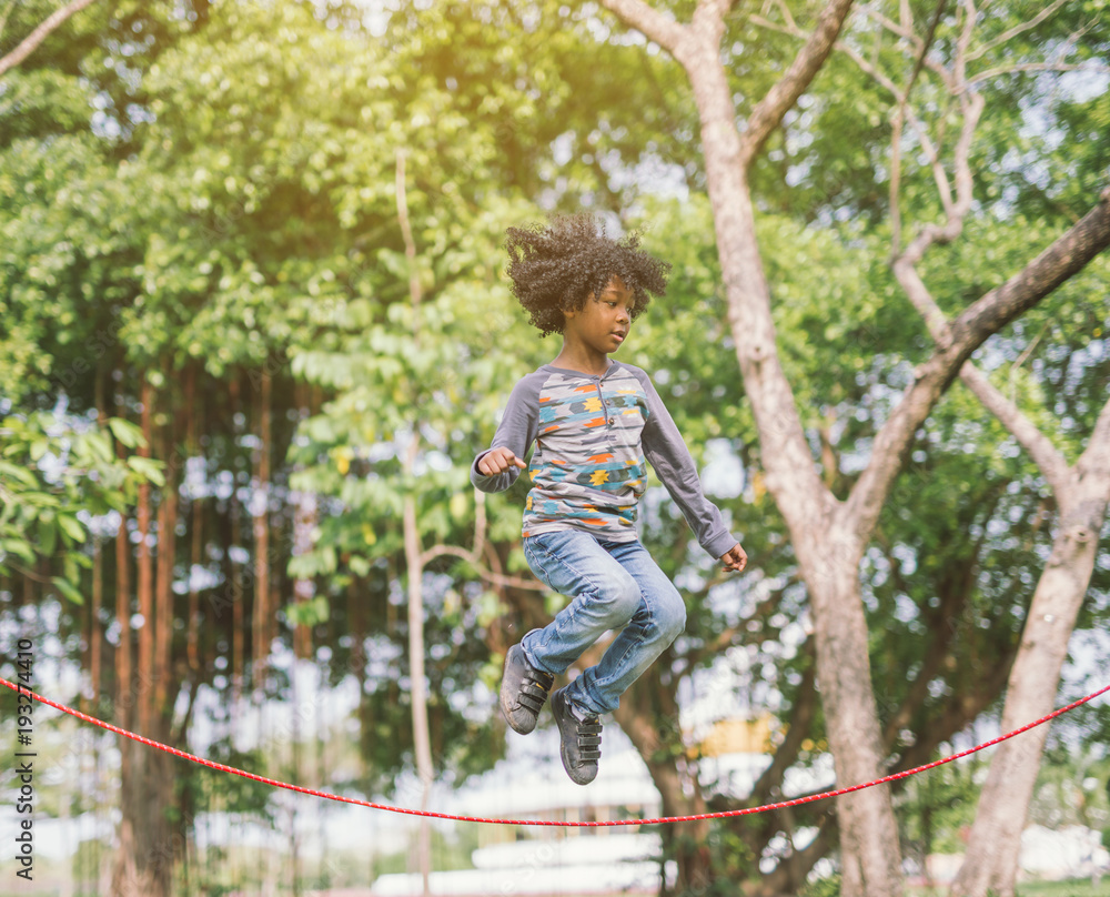 boy jumping over the rope in the park on sunny summer day