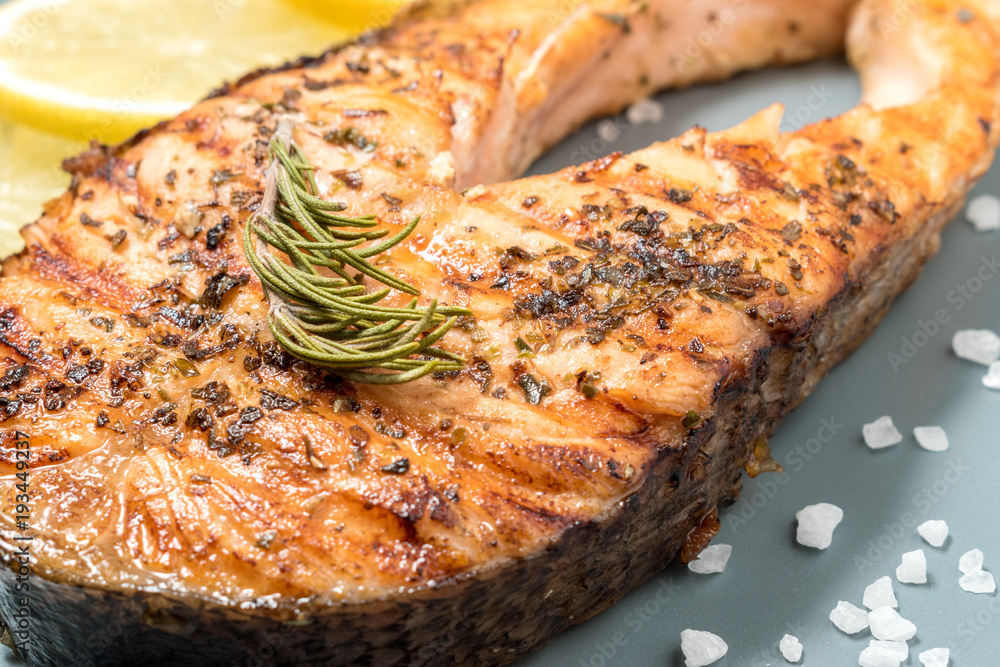 Salmon fillet. Grilled salmon with herb and lemon on plate. Fish roasted on a wooden background.