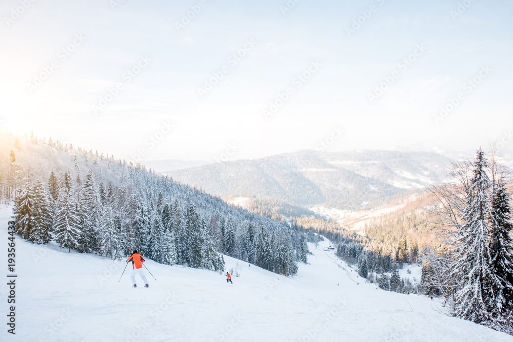 Landscape view on the beautiful Carpathian mountains with ski slope and skiers during the sunny weat