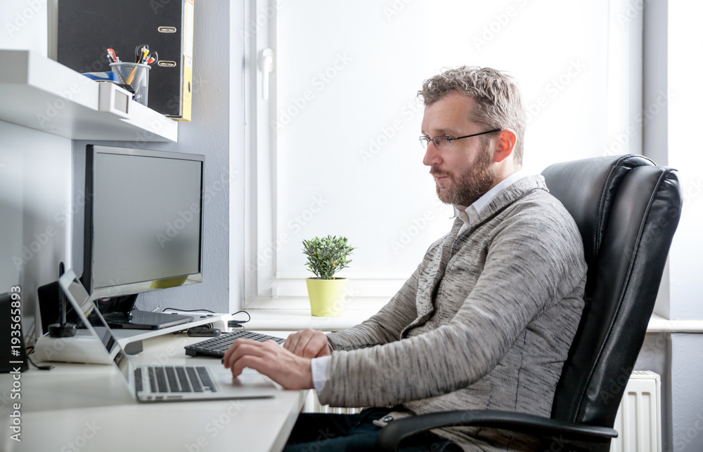 Middle age man working in home office with computer