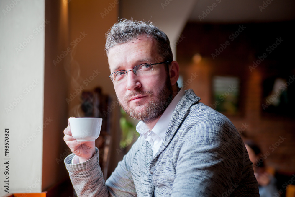 Confident man drinking cup of coffee in cafe