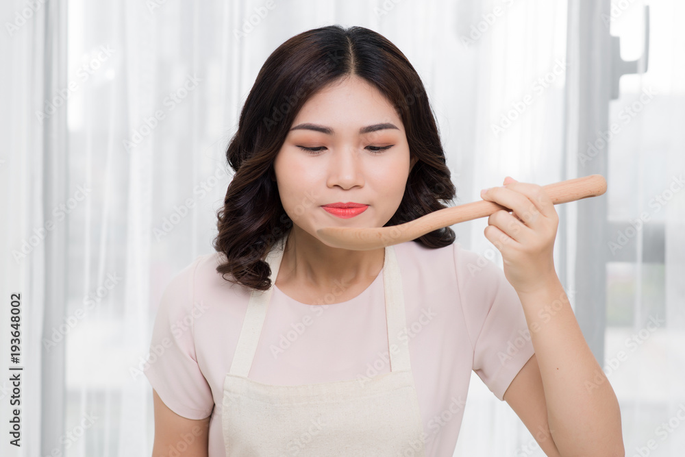 健康食品。亚洲女人在厨房用木勺做饭