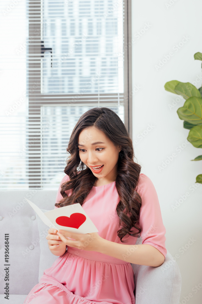 Cute girl reading a love card from her boyfriend