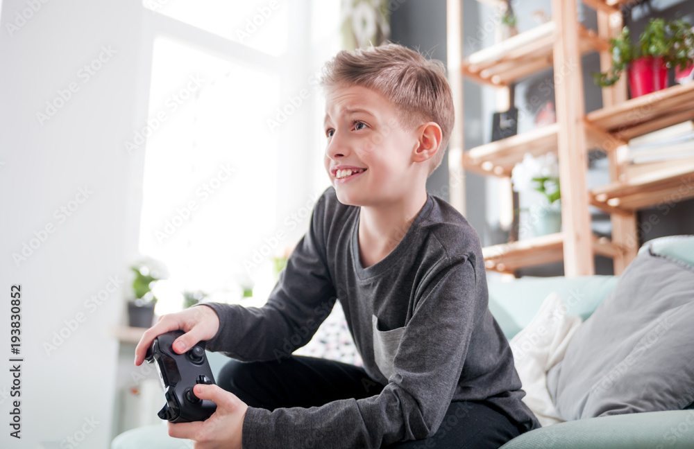 Excited young boy playing game on the console at home