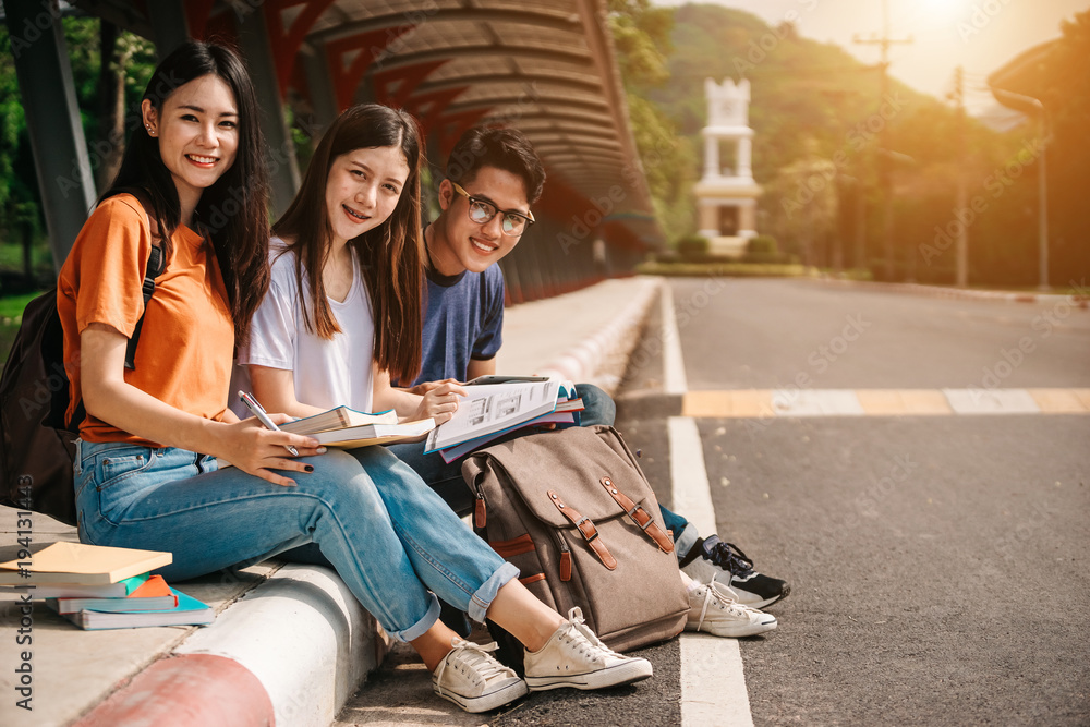 一群年轻或十几岁的亚洲学生在大学里微笑着读着书，看着ta