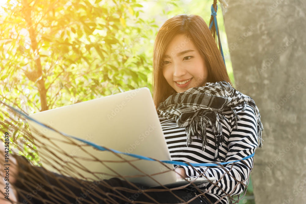 Young woman with scarf use laptop lying in hammock, freelance life style conceptual, work anywhere