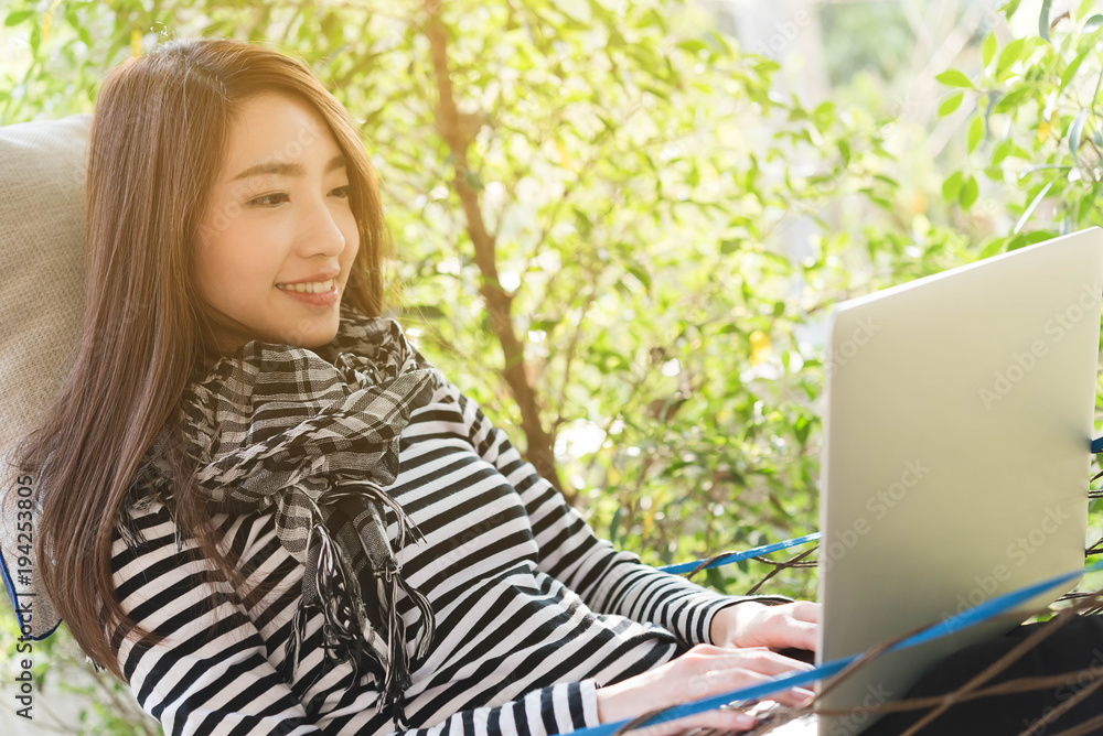 Young woman with scarf use laptop lying in hammock, freelance life style conceptual, work anywhere