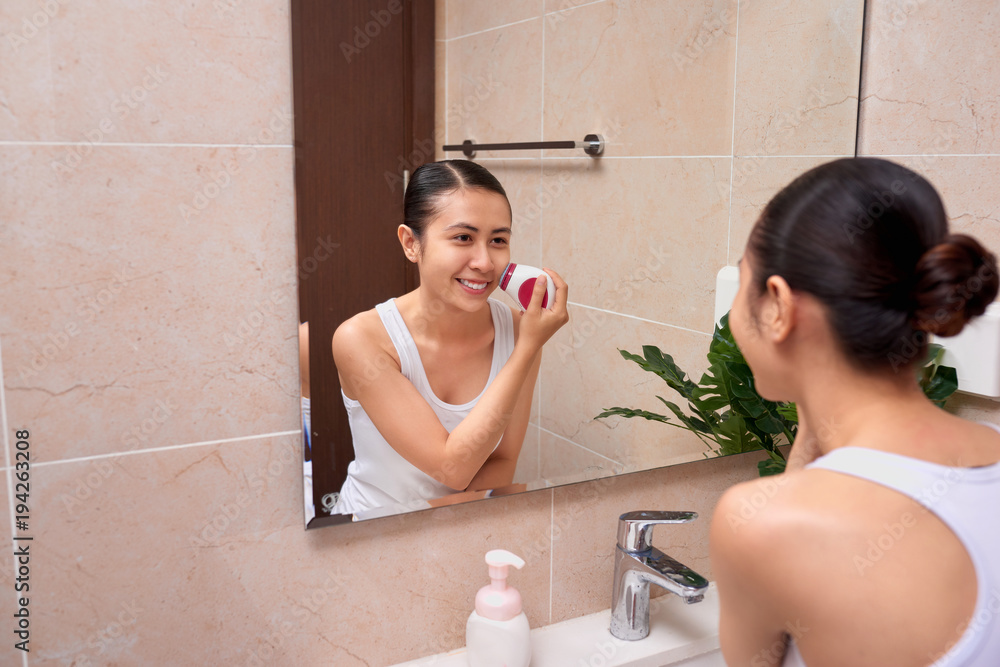 Portrait of young woman with perfect skin removing makeup with cleansing brush