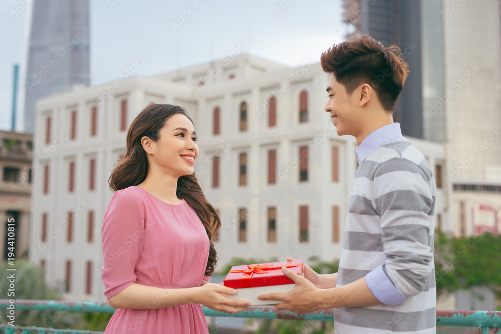 男人给女人送礼物。亚洲情侣在户外热恋