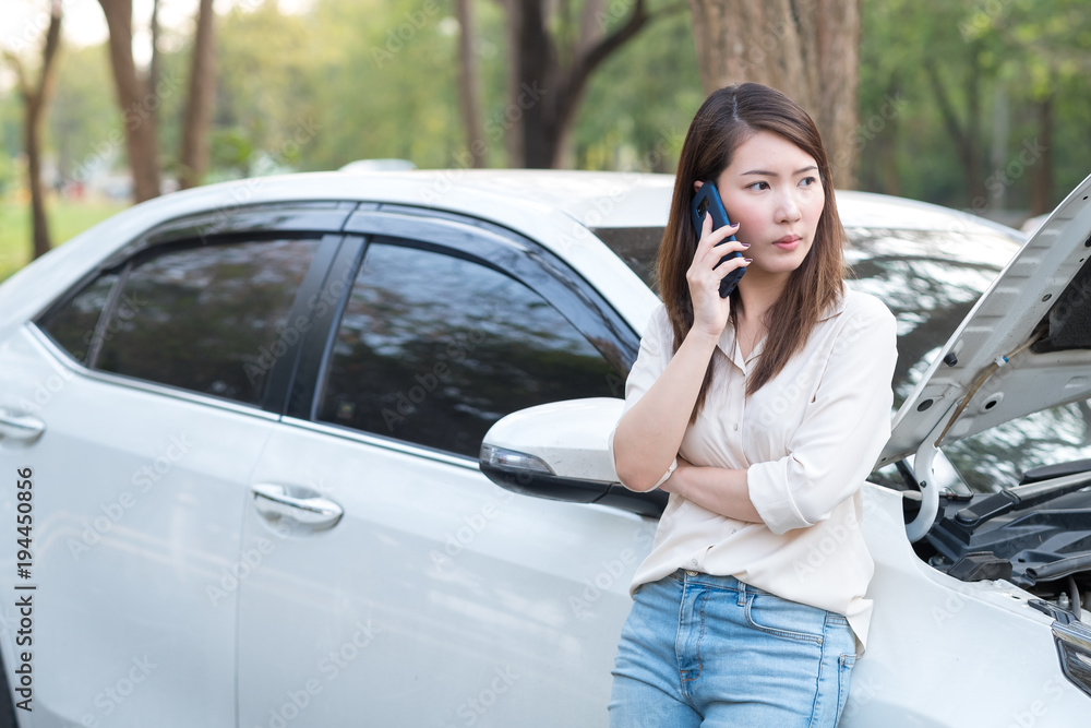 一名年轻的亚洲女子试图为她抛锚的汽车寻求帮助