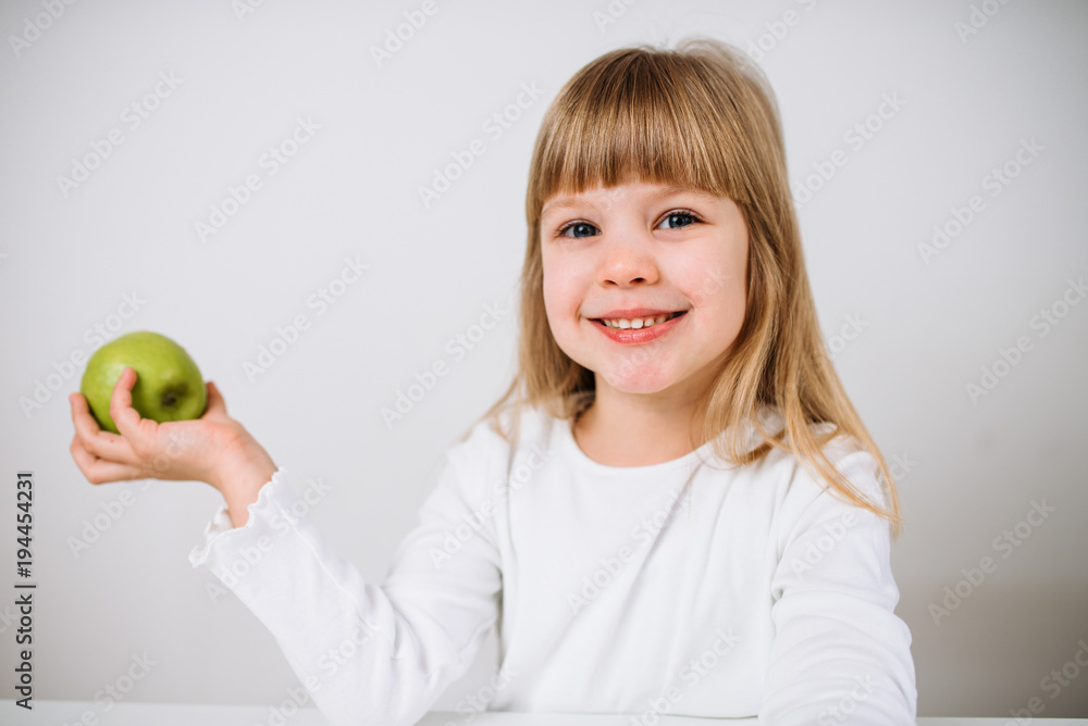 一天一个苹果让医生远离。一个小女孩在孤立的背景上抱着绿色的苹果。